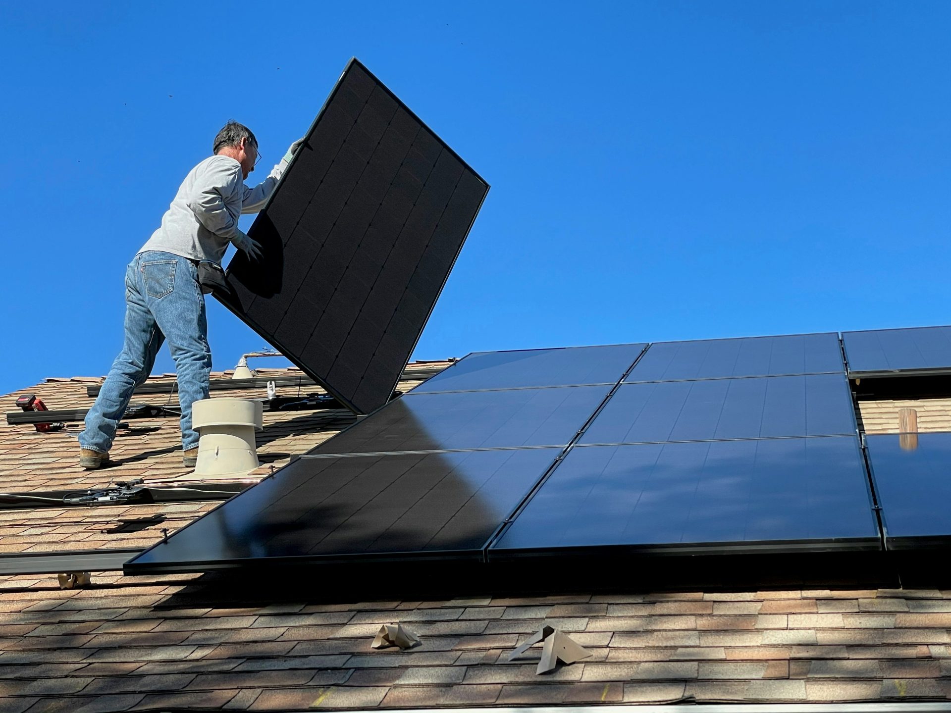 Mann im weißen Hemd und blauen Jeans sitzt auf einem weißen und schwarzen Solarpanel