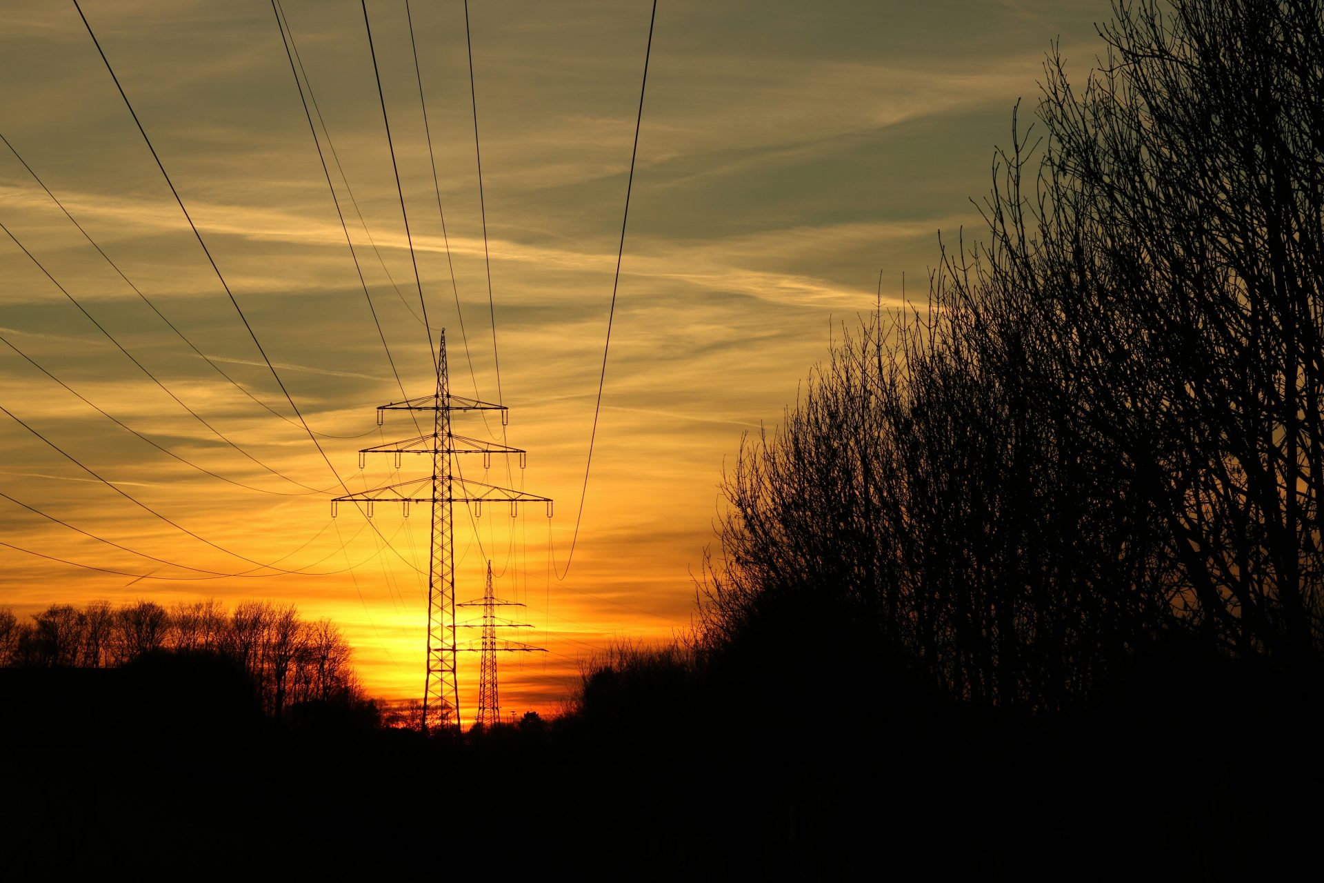 die Sonne geht hinter den Stromleitungen unter